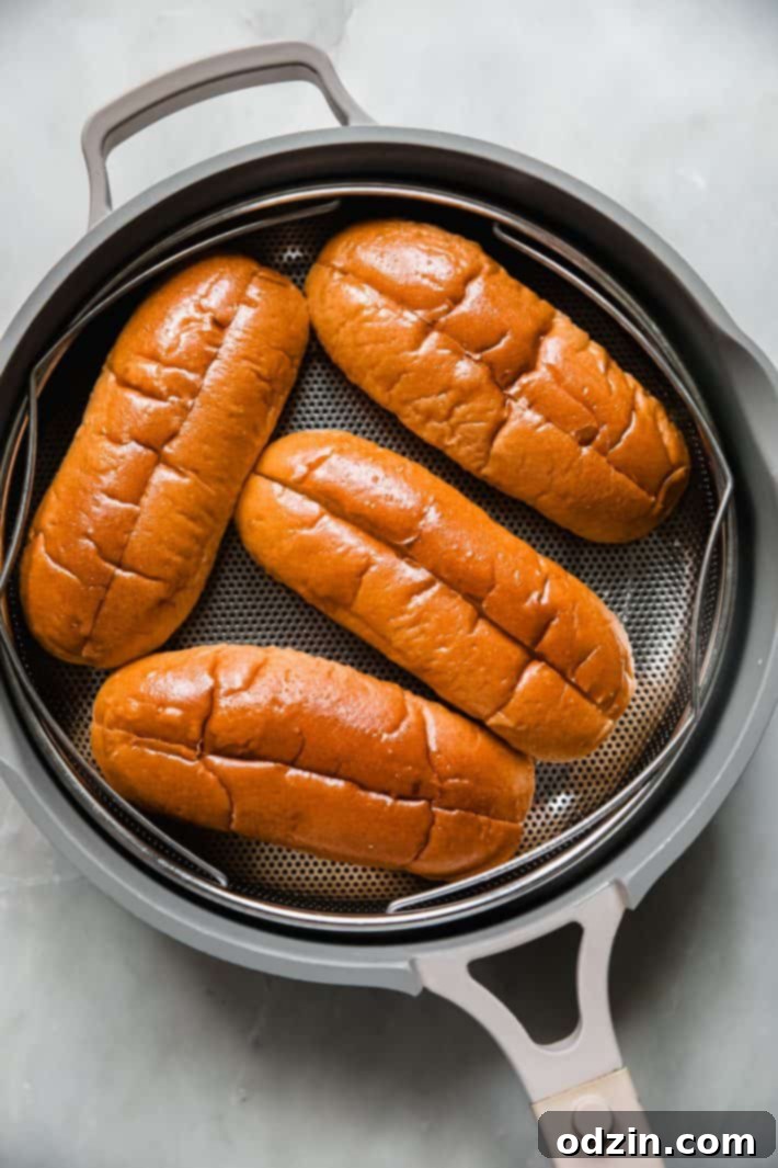 Steamed brioche hot dog buns resting in a metal pan, ready for assembly