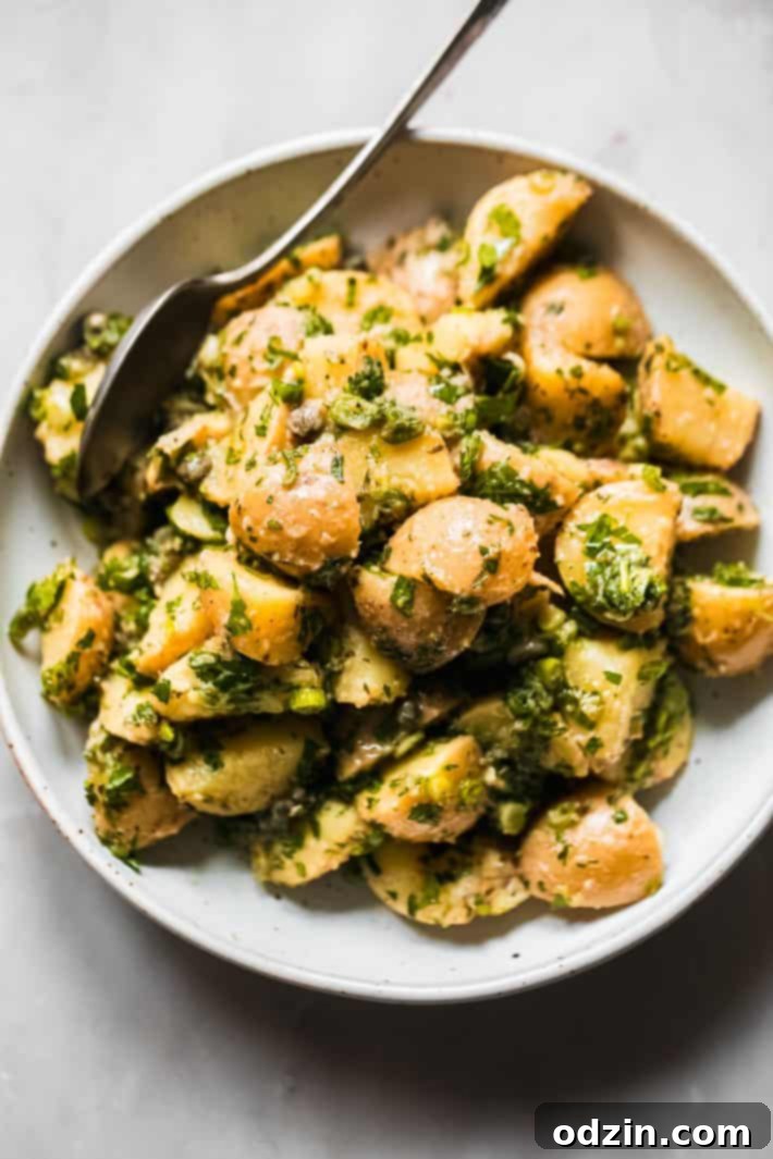 potato salad with no mayo in bowl topped with lots of fresh herbs