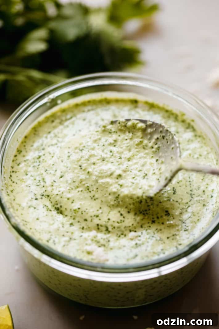 Peruvian Aji Verde Sauce 2 Vibrant Aji Verde (Peruvian Green Sauce) in a glass jar with a spoon, showcasing its rich texture and color.