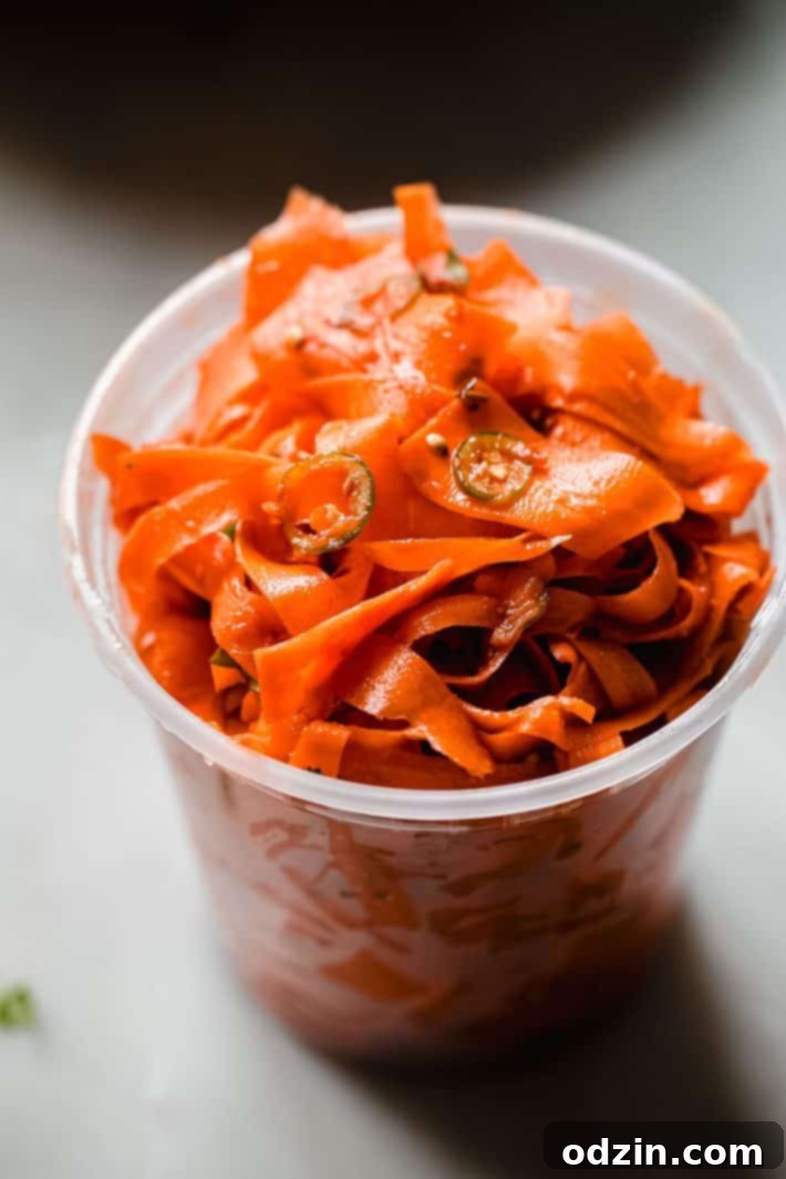carrot ribbon salad in jar topped with sliced serrano peppers