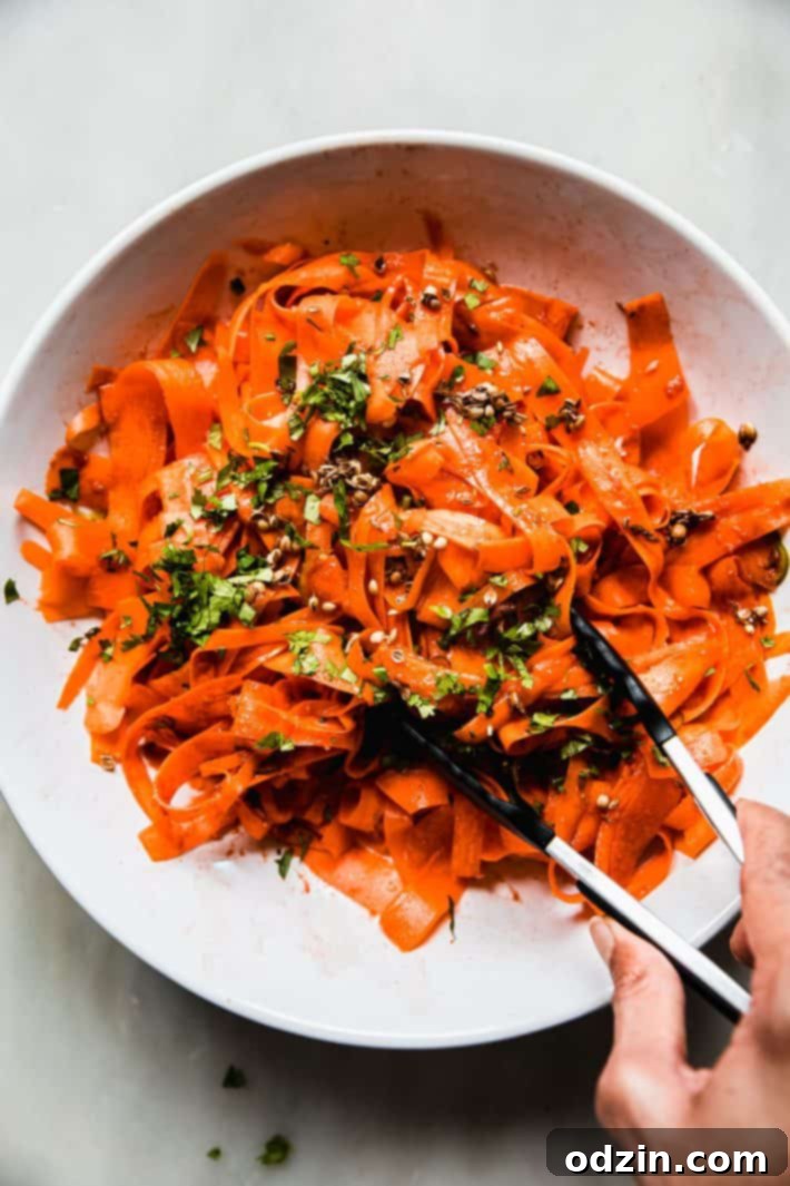 tossing raw carrot salad with tongs