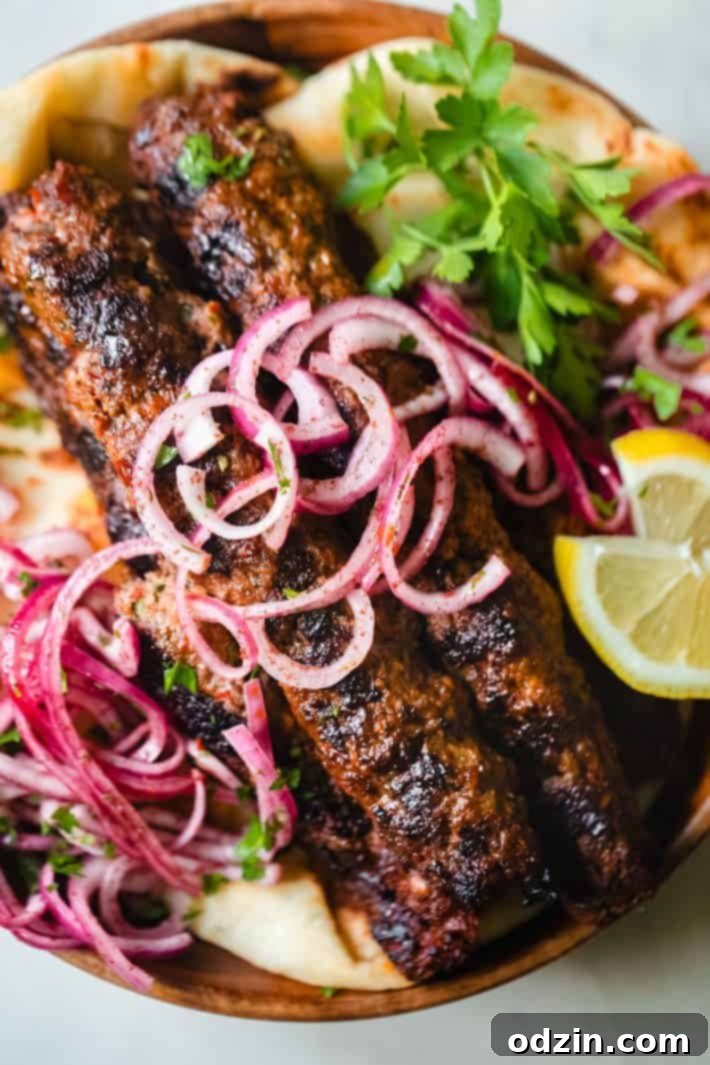 sumac onions and Adana Kebab on plate with lemon and parsley