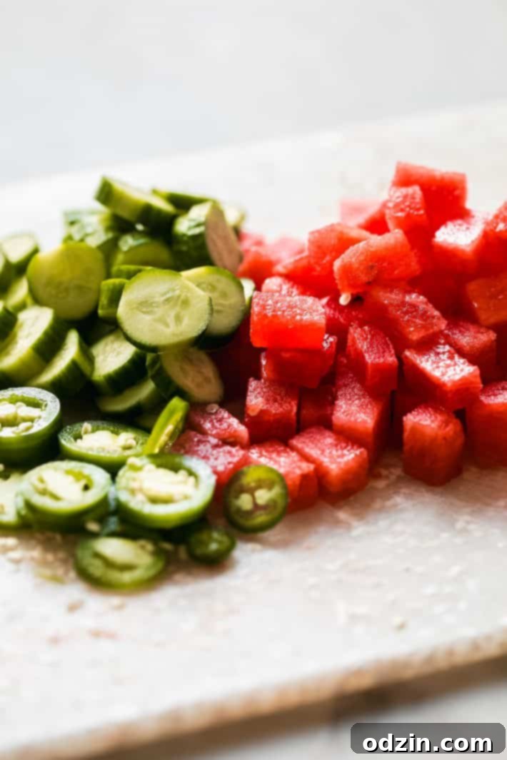 cubed watermelon, cucumber slices and sliced jalapeno on cutting board