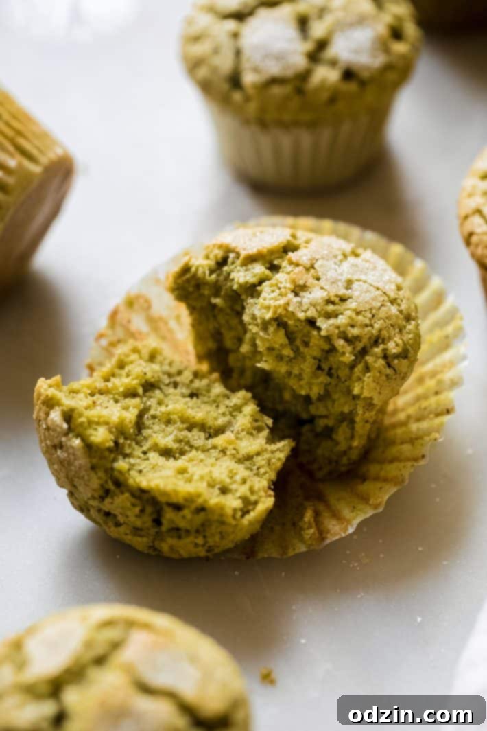 Perfectly Pistachio Muffins: Bakery Quality, Pudding-Free 3 A pistachio muffin broken in half, revealing its tender, green crumb texture speckled with pistachios, cardamom, and rosewater.