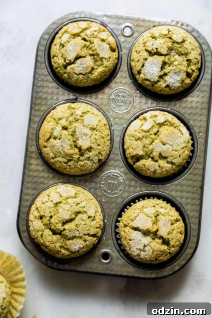 Perfectly Pistachio Muffins: Bakery Quality, Pudding-Free 5 A muffin tin filled with freshly baked pistachio muffins, topped with a beautiful sugary crust, cooling on a wire rack.