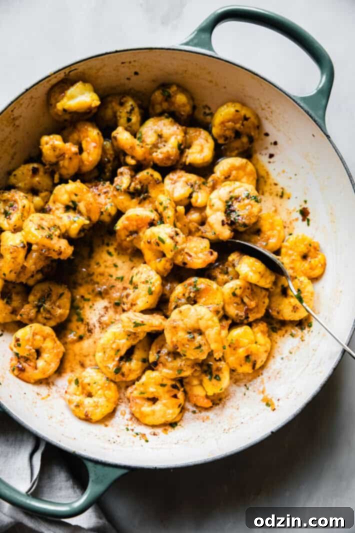 Sizzling shrimp with vibrant saffron butter sauce in a cast iron pan, ready to be served.