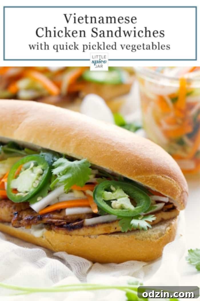 Beautifully assembled Vietnamese Chicken Banh Mi sandwiches on a striped cloth, showcasing fresh bread, tender chicken, pickled vegetables, and fresh jalapeños.
