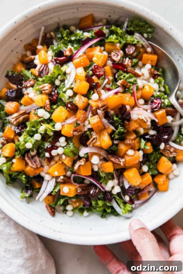 Autumn Glow: Roasted Butternut & Pearl Couscous Salad 2 hand holding autumn pearl couscous salad in bowl with spoon