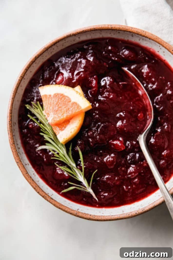 homemade cranberry sauce in bowl with orange slices and rosemary
