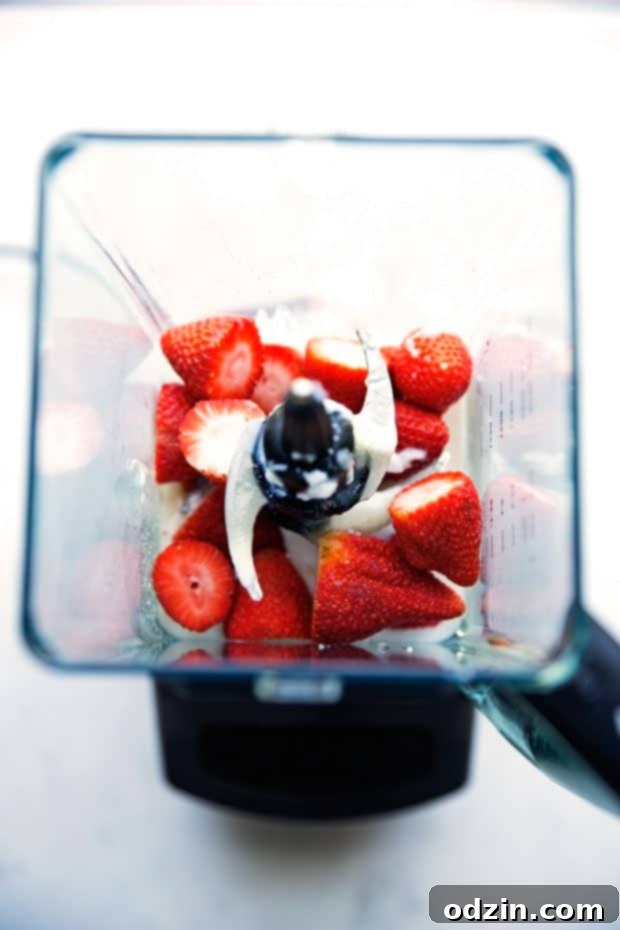 Two elegant glasses of homemade Strawberry Rose Lassi, garnished with fresh strawberry slices, ready to be served. Emphasizes the drink's beauty and appeal as an easy, delicious recipe for any gathering. Keywords: #easyrecipe #strawberrydessert #drinkrecipe #partyfavor