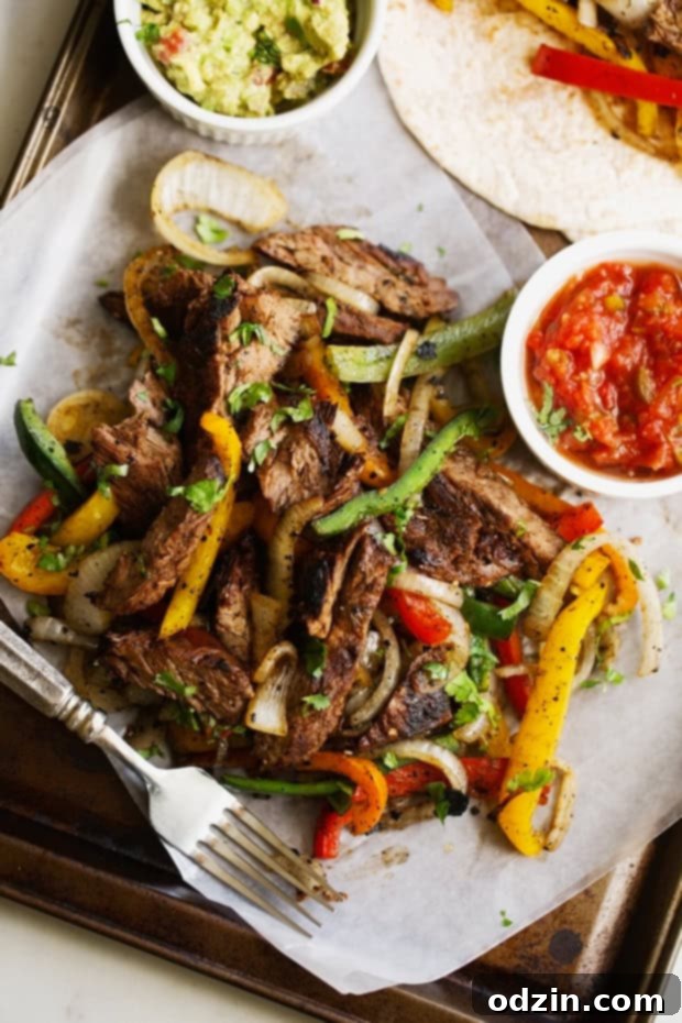 Sizzling Steak Fajita Perfection 5 thinly sliced steak fajitas with colorful peppers and onions on sheet pan