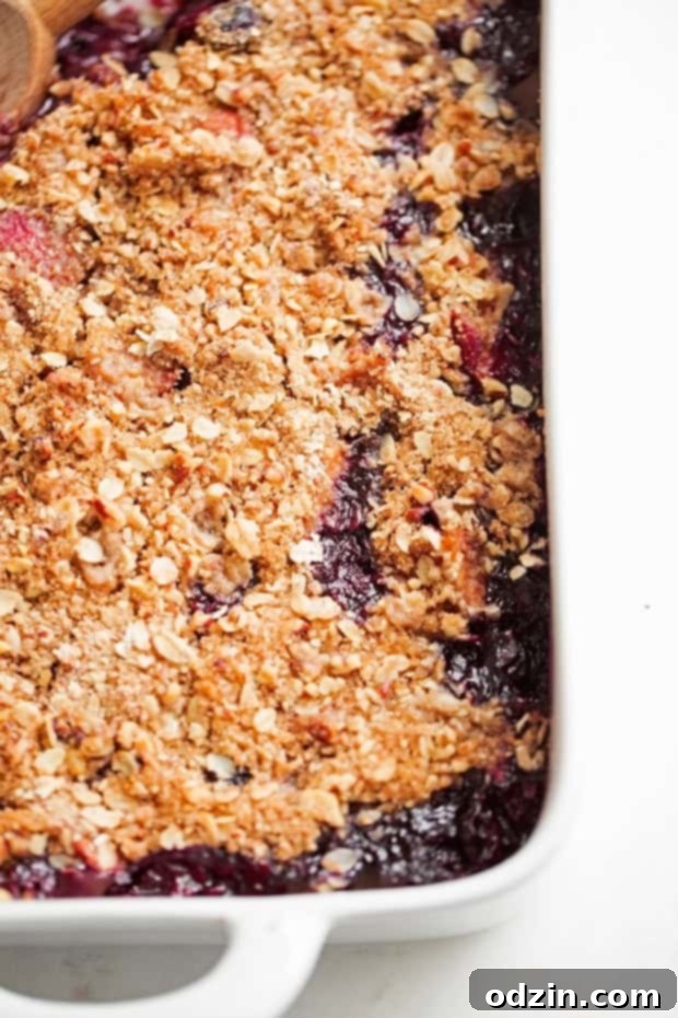 Homemade Blueberry Peach Crisp - A super summery dessert topped with a pecan and oat crumble #blueberrycrisp #peachcrisp #blueberrycrumble #peachcrumble | Littlespicejar.com A delicious spoonful of Blueberry Peach Crisp, showing the golden oats, sweet blueberries, and tender peaches. A perfect summer treat.