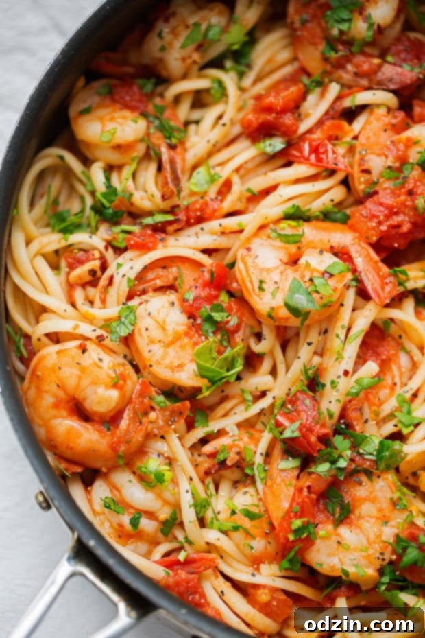 spicy shrimp pasta in saute pan tipped with fresh parsley