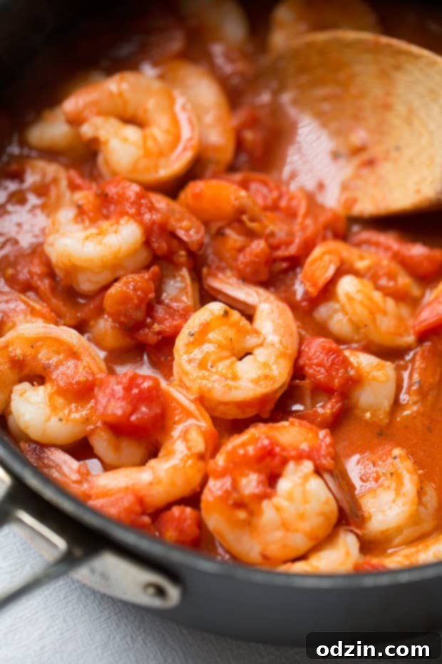spicy shrimp and tomato mixture in saute pan with wooden spoon