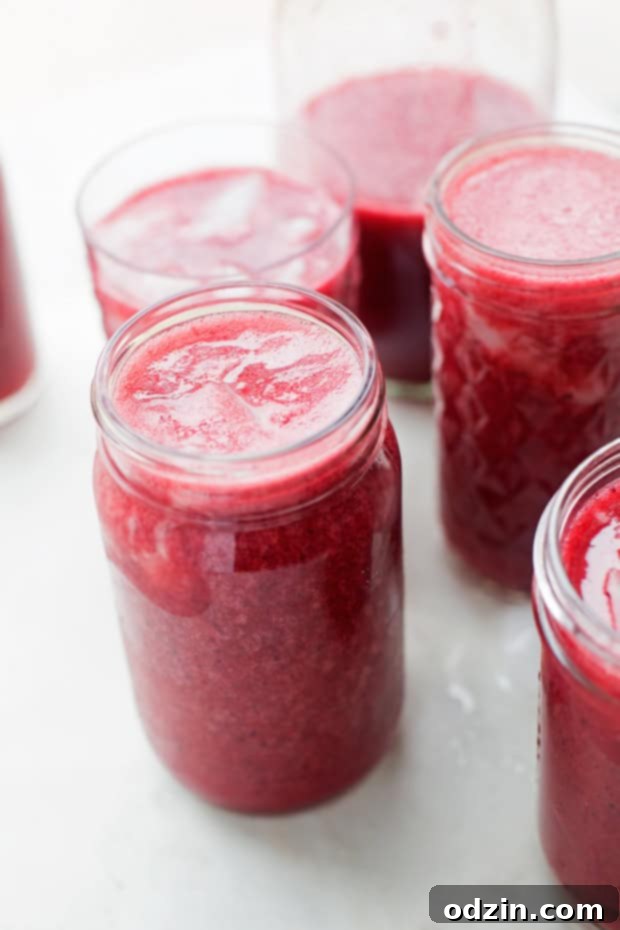 A tall glass of Mixed Berry Agua Frescas garnished with fresh berries and lime slices, sparkling with ice. The ultimate summer drink. #aguafrescas #berryaguafrescas #summerdrinks