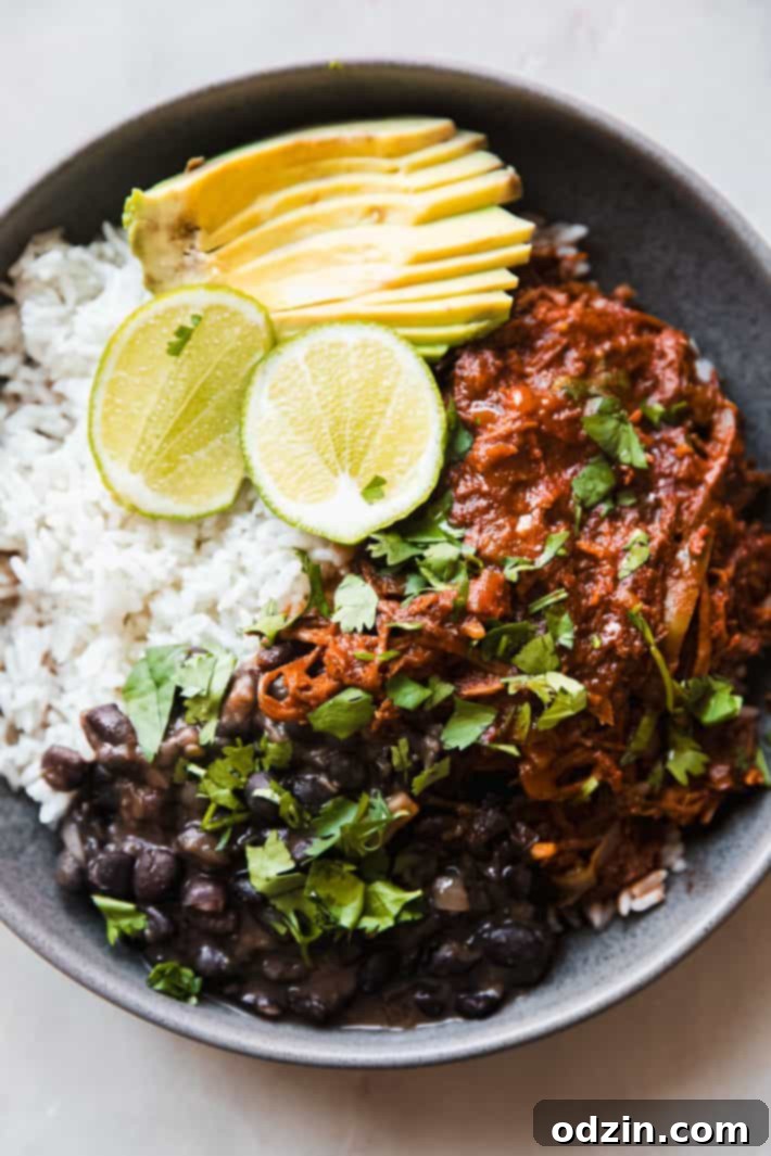 Melt-in-Your-Mouth Cuban Ropa Vieja 2 Close-up of tender Cuban Shredded Beef (Ropa Vieja) served with rice, black beans, and avocado.