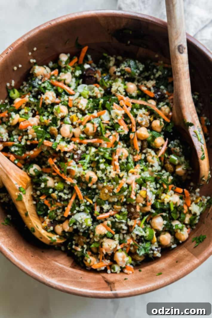 Moroccan Energy Quinoa Bowl 6 power salad in bowl with raisins, garbanzo beans, carrots, and wooden spoons