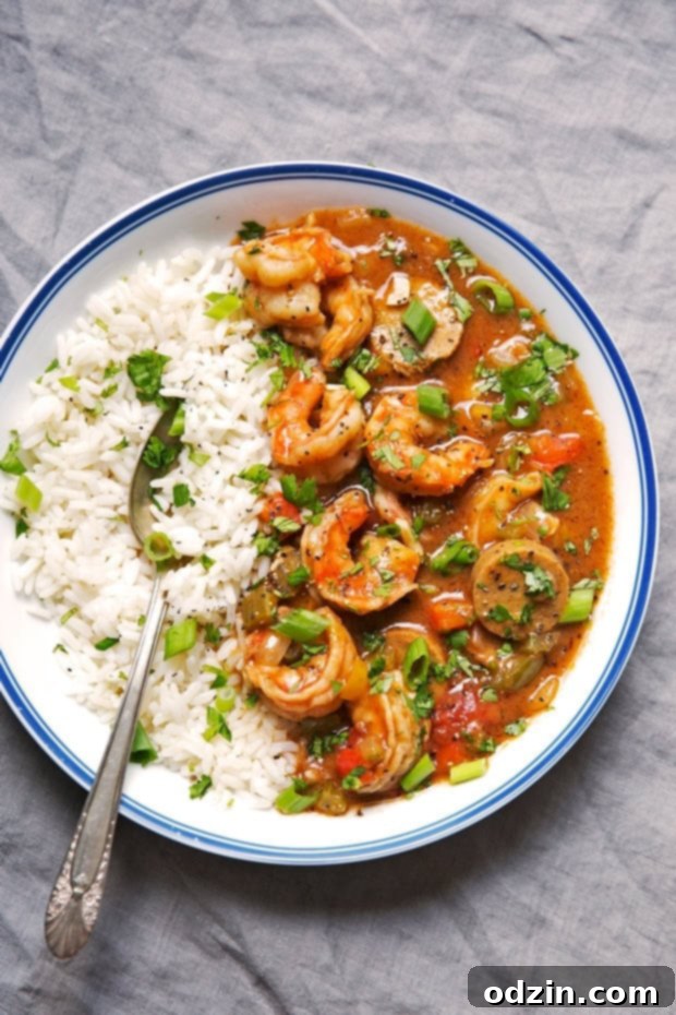 New Orleans Shrimp and Sausage Gumbo 6 bowl with gumbo on one side and white rice on the other with spoon in blue rimmed bowl