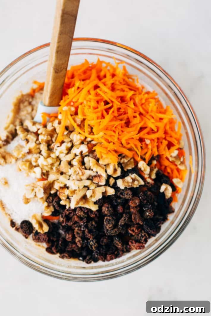 Delicious and healthy carrot cake muffins with a close-up of the moist interior, showing carrots, coconut, and walnuts. A delightful recipe from Littlespicejar.com