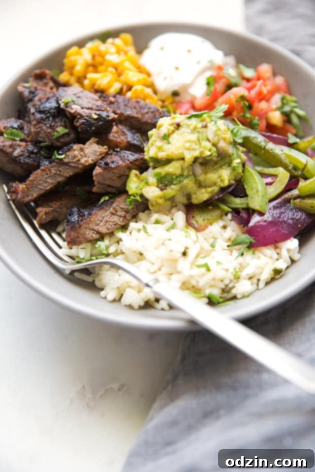 Homemade steak fajita bowls with garlic lime rice. These fajita bowls taste even better than the ones at Chipotle! The secret is the homemade marinade for the steak... it is to DIE for! #steakfajita #steakfajitabowls #fajitabowls #bowls | littlespicejar.com