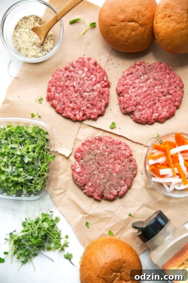 Hand seasoning a raw beef patty with garlic powder, onion powder, salt, and pepper for Banh Mi Burgers.