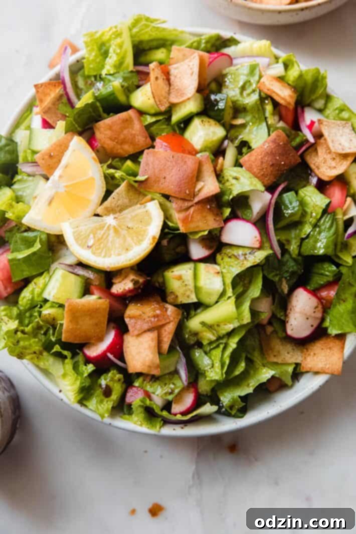 prepared fattoush salad with pita chips and dressing in speckled bowl