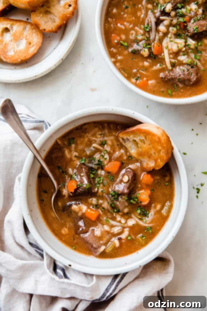 bowlful of beef barley soup with spoon and toasted bread