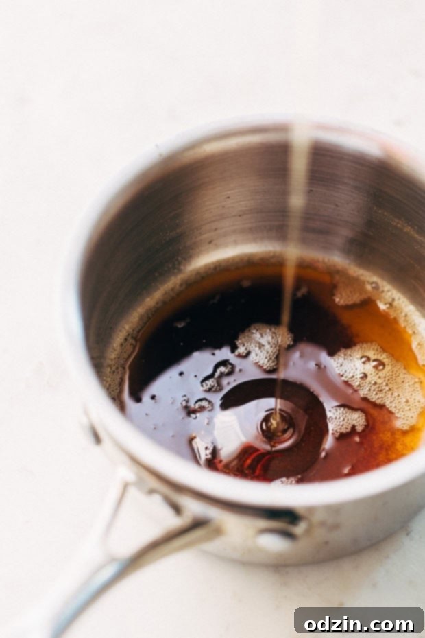 Close-up of golden brown butter simmering in a saucepan, highlighting the rich color and foam as it develops its nutty aroma.