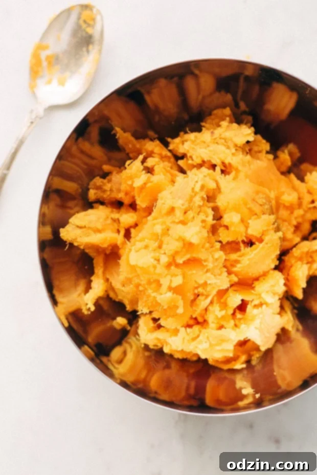 A bowl of mashed sweet potatoes mixed with butter, sugar, and eggs, before adding cream and vanilla.