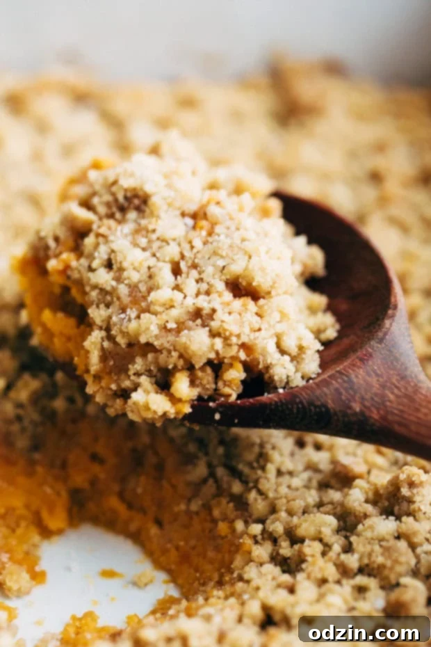 Sweet potato casserole spread in a baking dish, topped with the crunchy brown sugar and walnut mixture, ready for the oven.