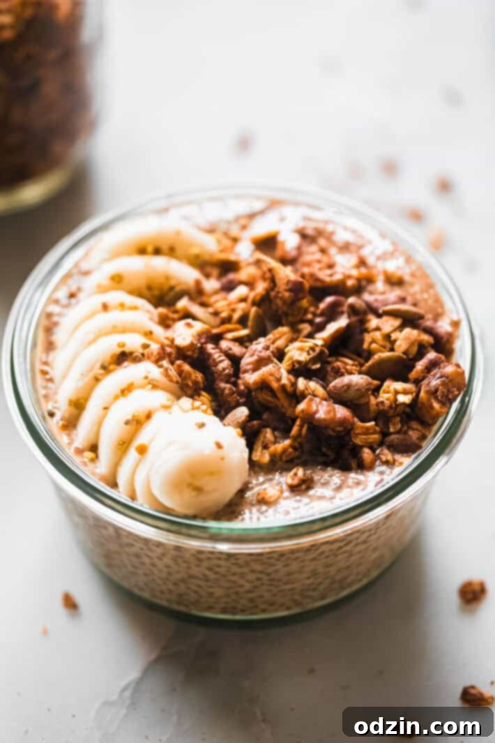 A bowl of pumpkin chia seed pudding, artfully arranged with toppings on a white surface, with autumn leaves and a small pumpkin in the background, creating a cozy fall aesthetic.