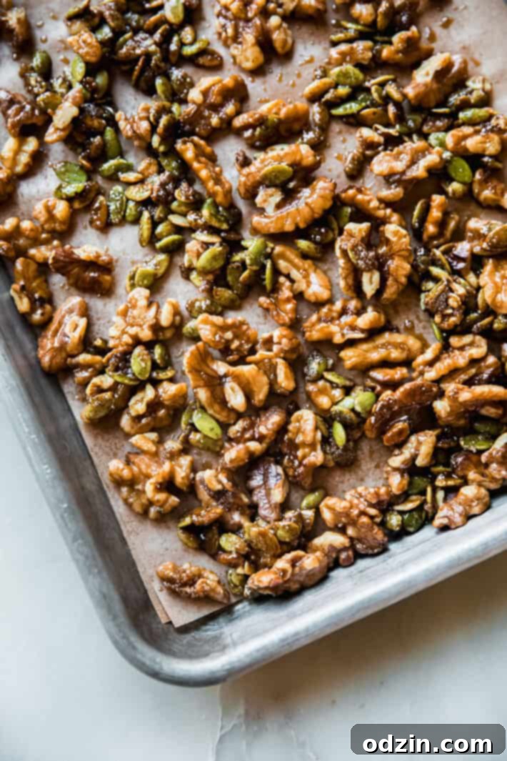 Candied walnuts and pumpkin seeds cooling on a baking sheet lined with parchment paper after being perfectly caramelized and seasoned