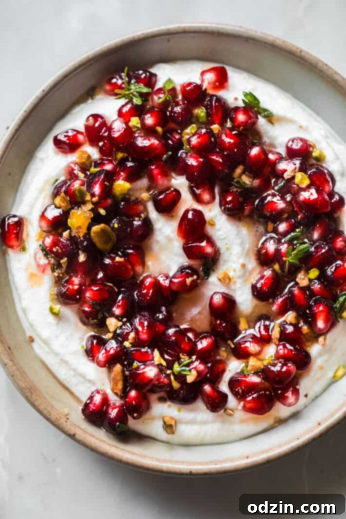 Close-up of whipped ricotta dip with vibrant pomegranate arils on top, sprinkled with green pistachios, inviting and festive.
