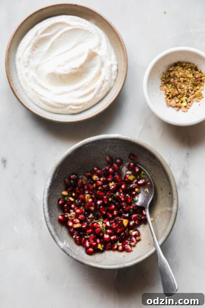 A bowl of beautifully prepared whipped ricotta dip, topped with glistening pomegranate arils, chopped pistachios, and sprigs of fresh thyme.